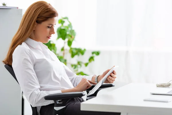 Вид сбоку на предпринимательницу, использующую цифровой планшет за столом в офисе — стоковое фото