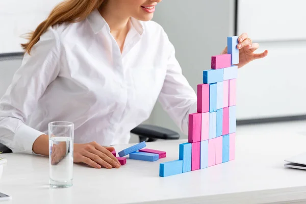 Cropped view of smiling businesswoman stacking marketing pyramid from building blocks on table — Stock Photo