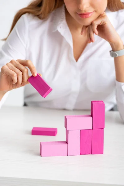 Selective focus of businesswoman stacking marketing pyramid with pink building blocks isolated on grey — Stock Photo