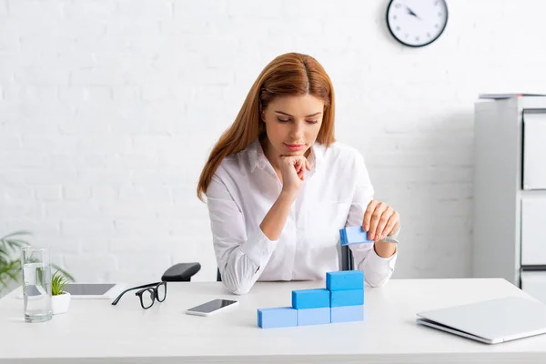 Attrayant femme d'affaires empilant pyramide de marketing de blocs de construction bleus sur la table — Photo de stock