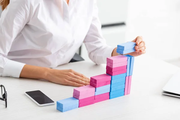 Ausgeschnittene Ansicht einer Geschäftsfrau, die Marketing-Pyramide aus Bausteinen auf dem Tisch stapelt — Stockfoto