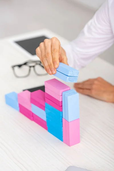 Ausgeschnittene Ansicht einer Geschäftsfrau, die aus bunten Bausteinen auf dem Tisch eine Marketing-Pyramide bastelt — Stockfoto