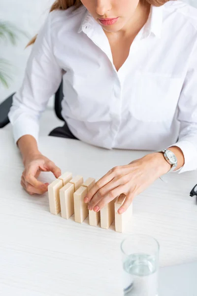 Cropped view of businesswoman stacking wooden building blocks on table — Stock Photo
