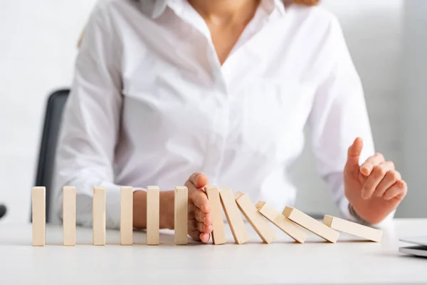 Selective focus of businesswoman holding falling building blocks on table — Stock Photo