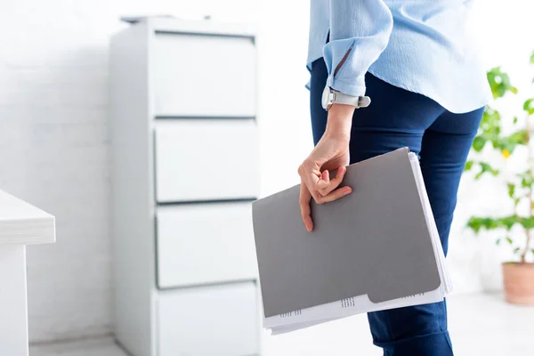 Обрезанный вид деловой женщины, держащей папку с досье в офисе — стоковое фото