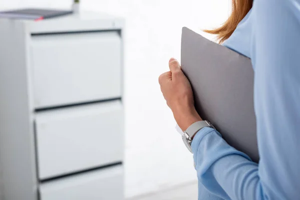 Обрезанный вид предпринимательницы держащей бумажную папку в офисе — стоковое фото