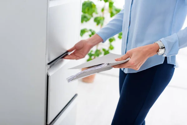 Cropped view of businesswoman holding folder with dossier and opening cabinet driver — Stock Photo
