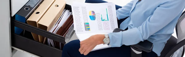 Ausgeschnittene Ansicht einer Geschäftsfrau, die Papiere mit Diagrammen in der Nähe eines offenen Schranktreibers mit Papiermappen hält, Panoramaaufnahme — Stock Photo