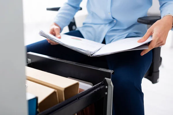 Vista cortada de empresária segurando pasta com papéis perto do driver do gabinete aberto no fundo branco — Fotografia de Stock