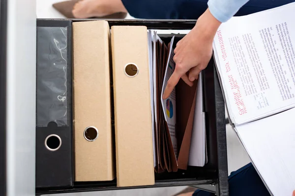 Vista dall'alto della donna d'affari che cerca documenti nel driver del gabinetto con le cartelle di carta — Foto stock