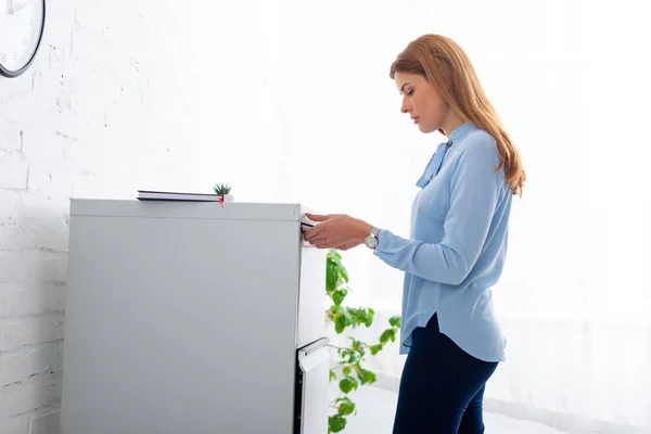 Vista laterale della donna d'affari che apre il driver del gabinetto in ufficio — Foto stock