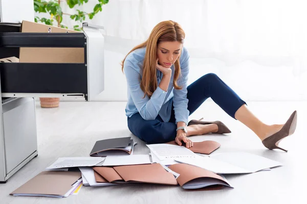 Atractiva mujer de negocios mirando contrato y documentos cerca del conductor del gabinete abierto en el piso - foto de stock