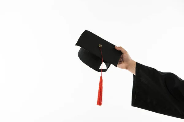 Обрізаний вид студента з витягнутою рукою, що тримає випускну шапку ізольовано на білому — стокове фото