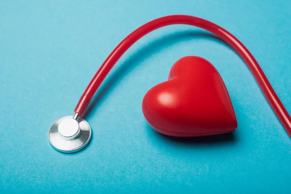 Corazón decorativo y estetoscopio rojo sobre fondo azul, concepto del día mundial de la salud - foto de stock