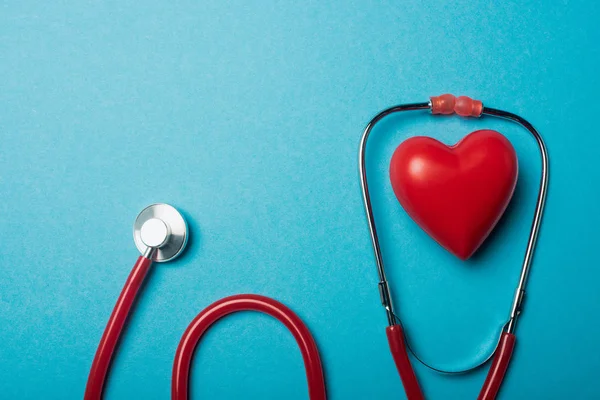 Top view of red heart and stethoscope on blue background, world health day concept — Stock Photo