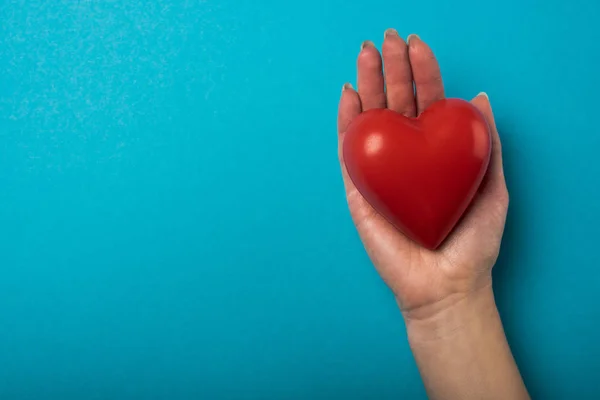 Vista dall'alto della donna che tiene decorativo cuore rosso su sfondo blu, concetto giornata mondiale della salute — Foto stock
