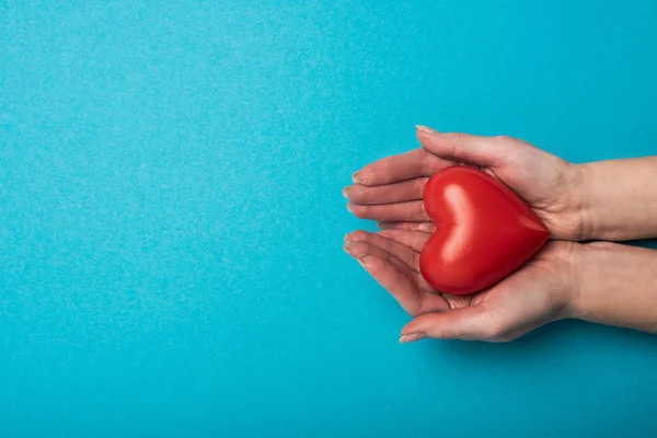 Vue du dessus de la femme tenant coeur décoratif sur fond bleu, concept de journée mondiale de la santé — Photo de stock