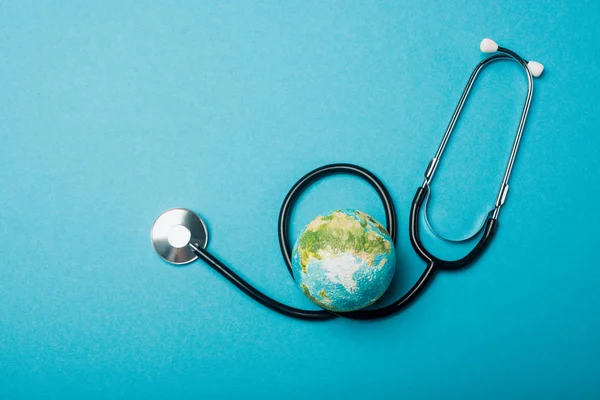 Weltkugel und Stethoskop von oben auf blauem Hintergrund, Konzept zum Weltgesundheitstag — Stockfoto