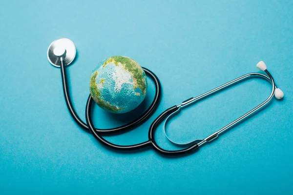 Globo y estetoscopio sobre fondo azul, concepto del día mundial de la salud - foto de stock