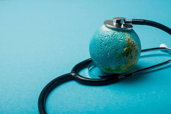 Estetoscopio conectado con el globo sobre fondo azul, concepto del día mundial de la salud - foto de stock