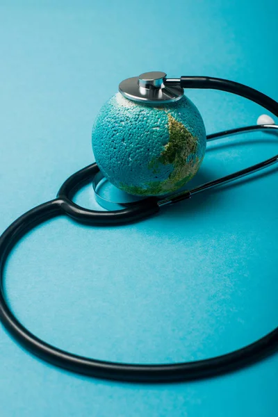 Black stethoscope connected with globe on blue background, world health day concept — Stock Photo