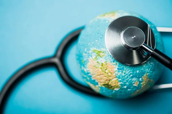 Foco seletivo do estetoscópio conectado com globo no fundo azul, conceito de dia mundial de saúde — Fotografia de Stock