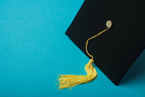 Casquette graduée avec pompon jaune sur fond bleu — Photo de stock