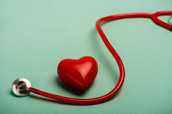 Decorative heart next to red stethoscope on green background, world health day concept — Stock Photo