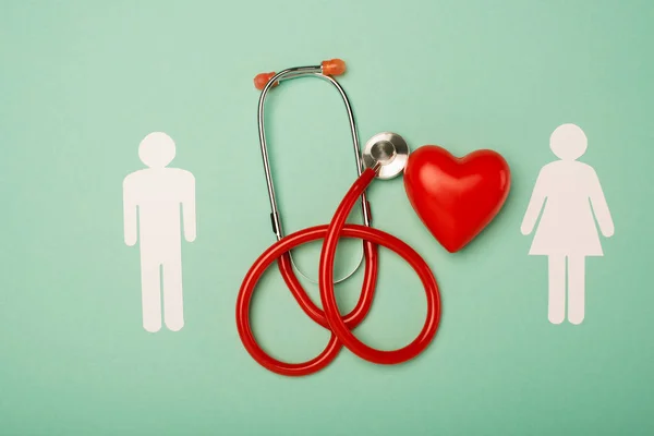 Top view of stethoscope, decorative red heart with male and female symbols on green background, world health day concept — Stock Photo