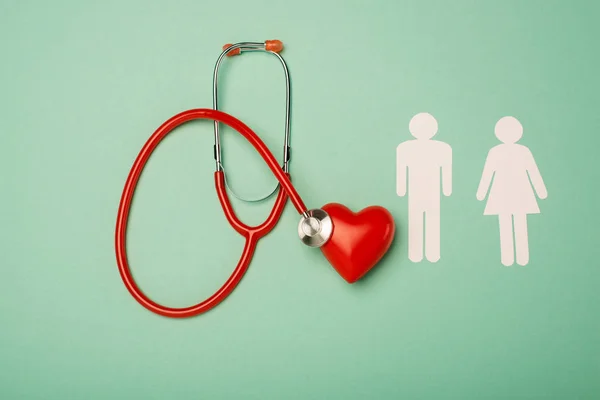 Вид зверху на стетоскоп, червоне серце з чоловічими та жіночими іконками на зеленому фоні, концепція Всесвітнього дня здоров'я — стокове фото