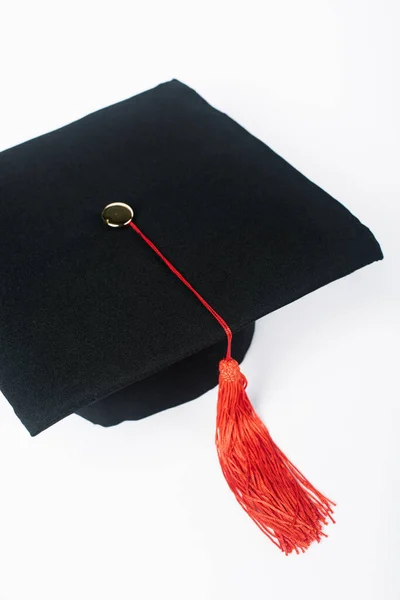 Schwarze Graduiertenmütze mit roter Quaste auf weißem Hintergrund — Stockfoto