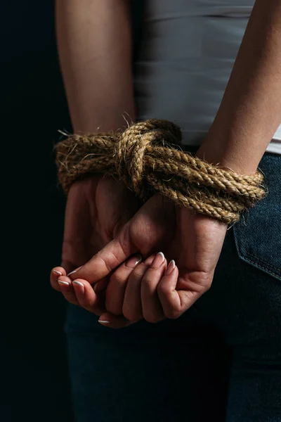 Частковий вигляд жіночих рук пов'язаних мотузкою ізольовані на чорному — стокове фото