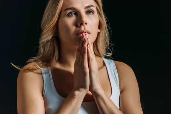 Mujer con las manos apretadas rezando aislada sobre negro - foto de stock