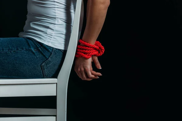 Cropped view of woman with tied hands on chair isolated on black — Stock Photo