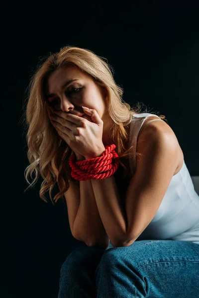 Bouche de couverture de victime bouleversée avec les mains liées isolées sur noir — Photo de stock