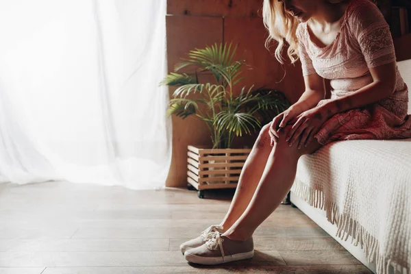 Cropped view of woman touching knee with bruises while sitting on sofa — Stock Photo