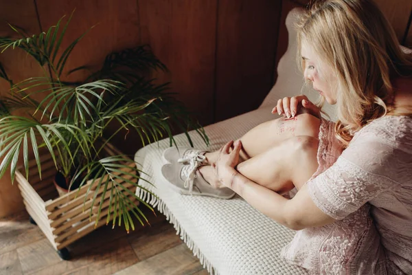 Femme soufflant sur la blessure et assise sur le canapé à la maison — Photo de stock