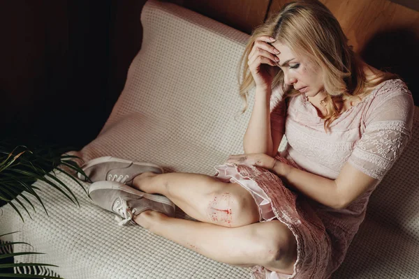 Thoughtful and upset woman with bruises on body sitting on sofa at home — Stock Photo