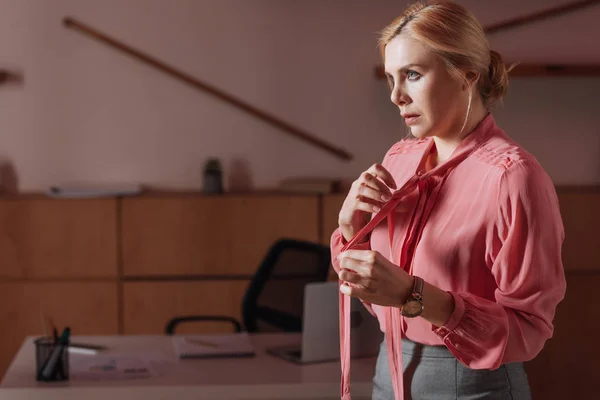 Enfoque selectivo de la mujer desatando cintas en la blusa en la oficina, concepto de acoso sexual - foto de stock