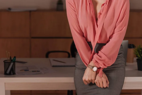 Обрезанный взгляд на женщину с сжатыми руками за столом в офисе, концепция сексуальных домогательств — стоковое фото