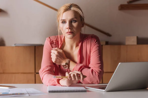 Selective focus of thoughtful and frustrated woman sitting at table in office, sexual harassment concept — Stock Photo