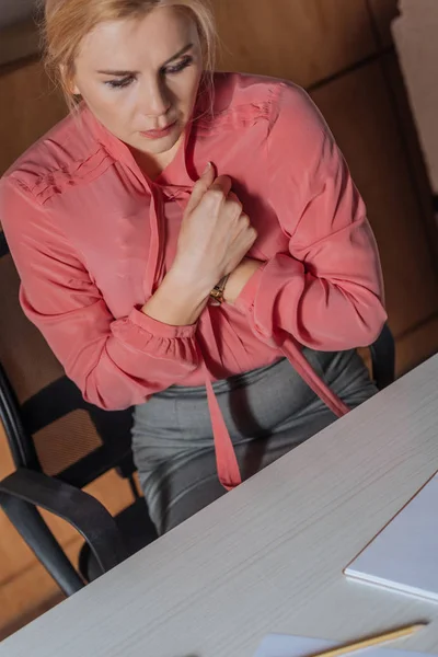 Mulher perturbada cobrindo o peito com blusa enquanto se senta à mesa no escritório, conceito de assédio sexual — Fotografia de Stock