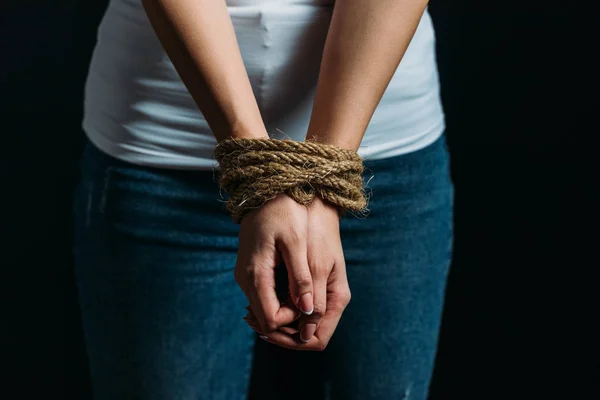 Cropped view of Victim hands tied with rope isolated on black — Stock Photo