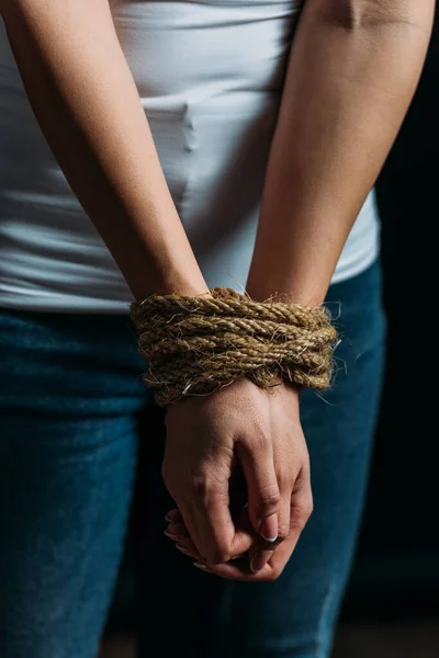 Обрізаний вид рук жертви, прив'язаних мотузкою, ізольовані на чорному — стокове фото