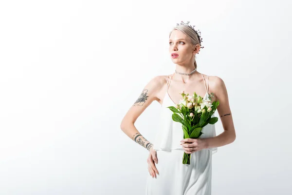 Bela noiva tatuada com buquê olhando para longe isolado no branco — Fotografia de Stock