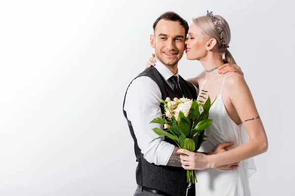 Happy beautiful tattooed bride and handsome bridegroom kissing isolated on white — Stock Photo