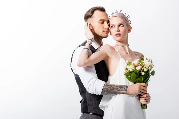 Beautiful tattooed bride and handsome bridegroom embracing isolated on white — Stock Photo