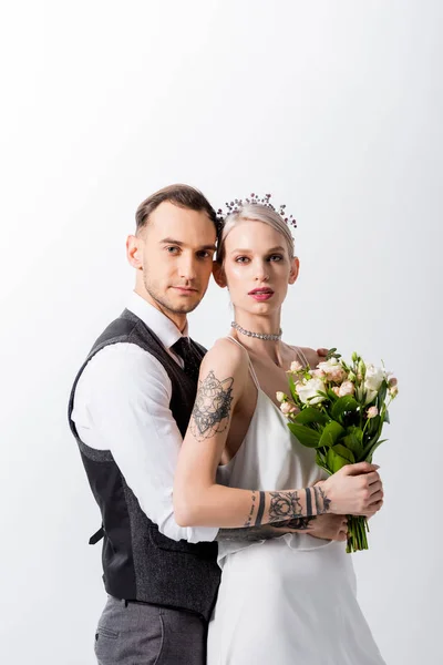 Beautiful tattooed bride and handsome bridegroom embracing isolated on white — Stock Photo