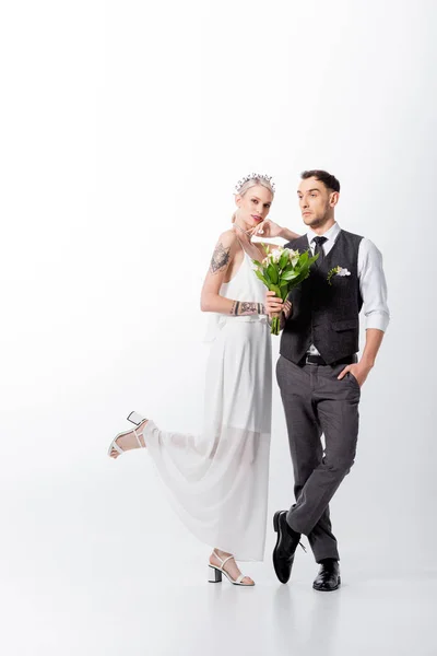 Beautiful tattooed bride and handsome bridegroom posing on white — Stock Photo