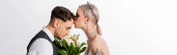 Side view of beautiful tattooed bride kissing handsome bridegroom isolated on white, panoramic shot — Stock Photo